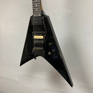 A black 1992 Carvin Ultra V USA electric guitar with a Kahler Steeler Trem, MJ-wound Seymour Duncan DCJ humbuckers, and multiple control knobs hangs against a light-colored wall.