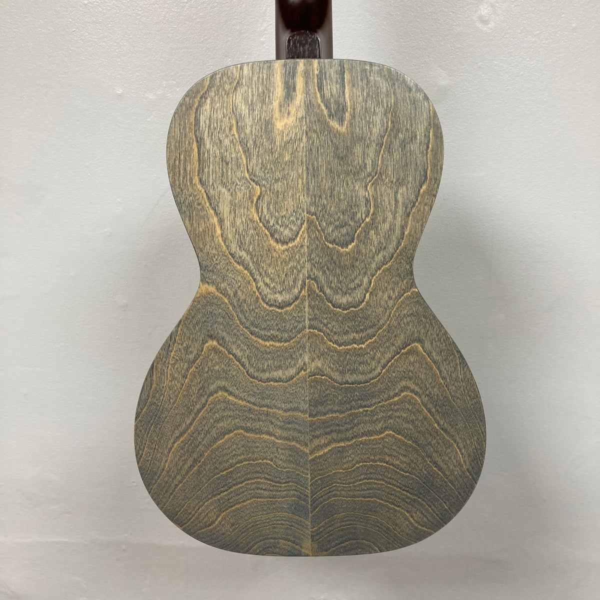 The back of the Art & Lutherie Roadhouse Denim Blue Q-Discrete Parlor Acoustic Guitar displays a wood grain pattern with wavy, symmetrical lines on a light-colored background.