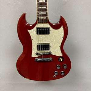 The Gibson SG Standard Heritage Cherry yr 2000 Consign by Gibson features a white pearloid pickguard, two humbuckers, four knobs, and a three-way switch, shown against a plain light background.