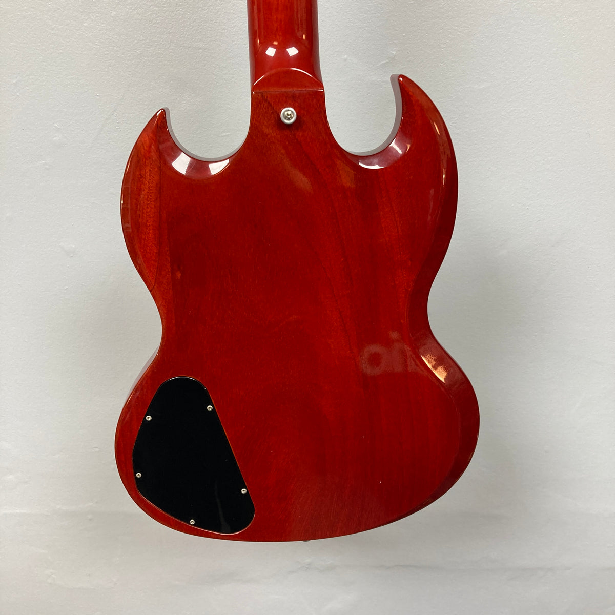 Back view of a Gibson SG Standard Heritage Cherry yr 2000 Consign electric guitar by Gibson, showing its glossy finish, rounded edges, and black cover plate on the lower left side against a plain white background.