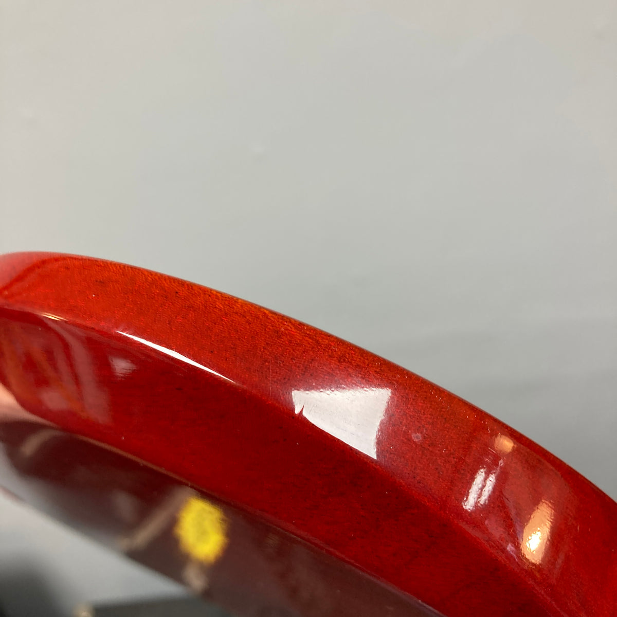 Close-up of the glossy, curved red body of a Gibson SG Standard Heritage Cherry yr 2000 Consign by Gibson, set against a plain gray background.
