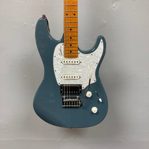 The Godin Session T-Pro Arctik Blue MN SF with Bag features a maple neck, white pickguard, HSS pickups, and tremolo bridge by Godin, displayed against a plain gray background.