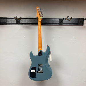 A Godin Session T-Pro Arctik Blue MN SF with Bag electric guitar by Godin hangs by its neck on a wall-mounted rack, shown from the back, unstrung, with a tag attached to one tuning peg.