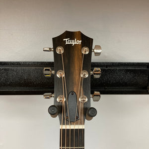 Close-up of a Taylor 212ce Plus w/Gigbag Used Consign headstock, showing six tuning pegs and strings against a plain background.
