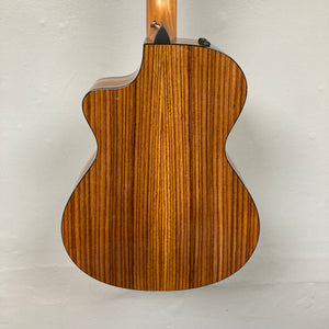 A close-up of the Taylor 212ce Plus w/Gigbag Used Consign highlights its natural wood grain back and elegant cutaway design.