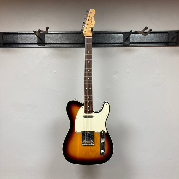 A Fender Heritage '60s Telecaster Custom Made in Japan Sunburst electric guitar with a white pickguard and two control knobs is displayed against a plain light gray background. Comes with gigbag; consign item.