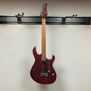 A Cort FW-G300 PRO electric guitar in Vivid Burgundy, featuring a maple neck, hangs on a black wall-mounted rack against a white wall.