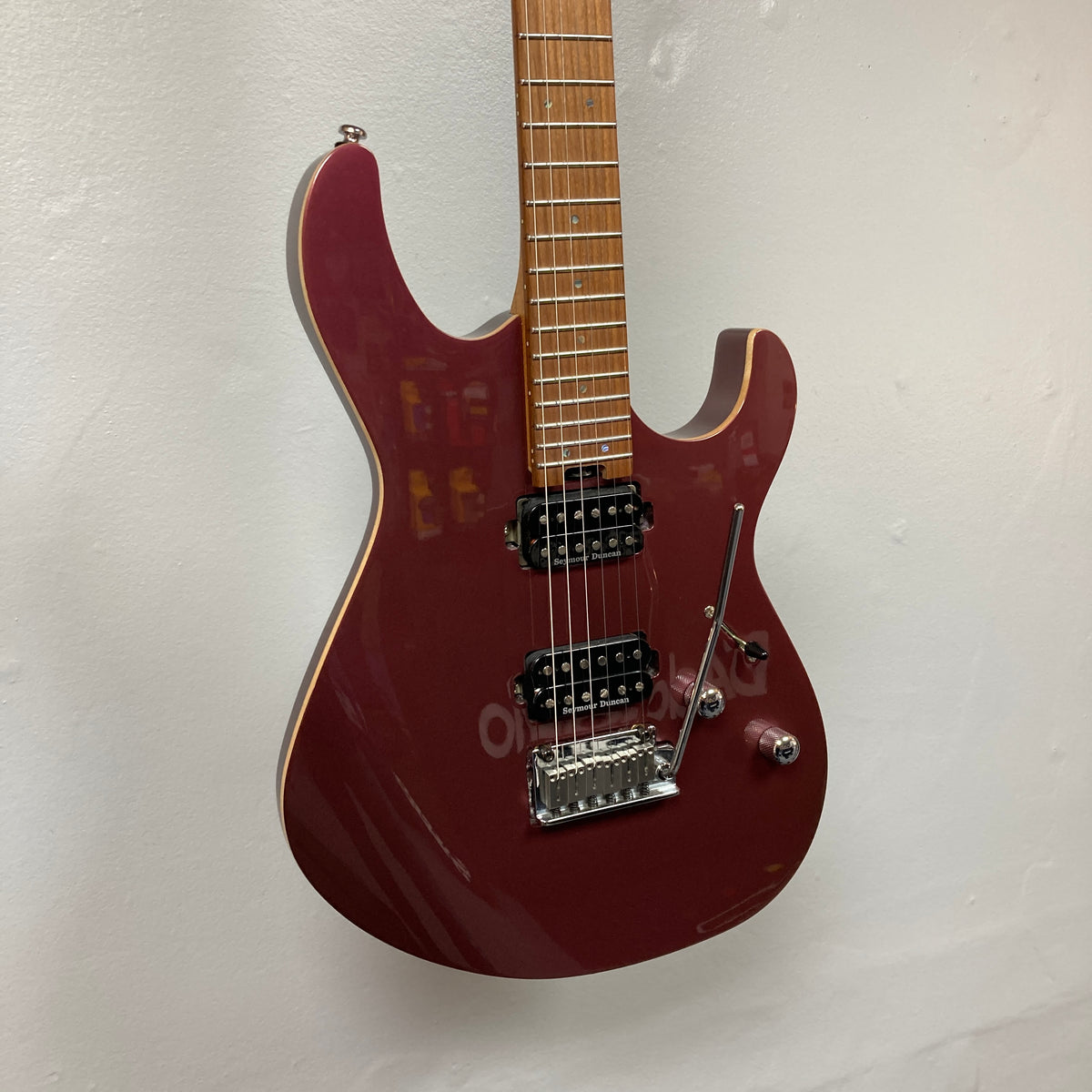 A Cort FW-G300 PRO electric guitar in vivid burgundy with a maple neck, two humbucker pickups, a tremolo bridge, and three control knobs, displayed on a white wall.