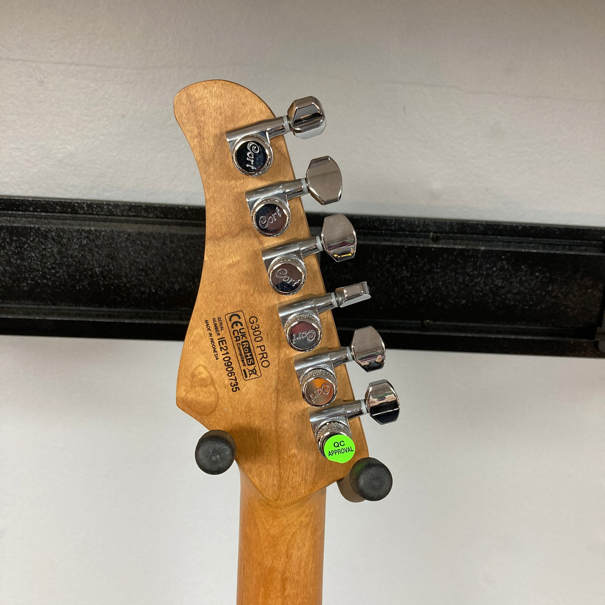 Close-up of the back of a Cort FW-G300 PRO Vivid Burgundy w/Gigbag Consign guitar headstock showing six tuning pegs, model and serial number information, and a green QC passed sticker.