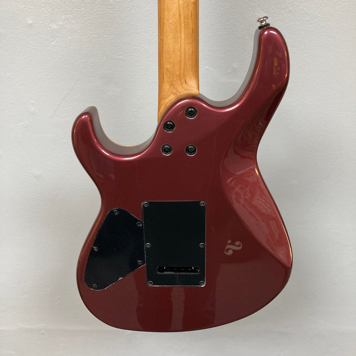 Sure! Here’s a revised sentence using your product data: The image shows the back of the Cort FW-G300 PRO Vivid Burgundy electric guitar by Cort, featuring a maroon finish, a natural wood neck, two black plastic backplates secured with four screws, all set against a white background.