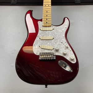 A Fender American Standard Strat upgraded Gilmour EMG DC-20 in Bordeaux Metallic, featuring a white pickguard and a maple neck, is hanging on a wall.