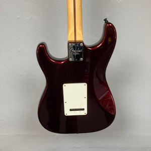The back of a Fender American Standard Strat upgraded Gilmour EMG DC-20 in Bordeaux Metallic is shown hanging on a gray wall, with the neck and backplate visible.