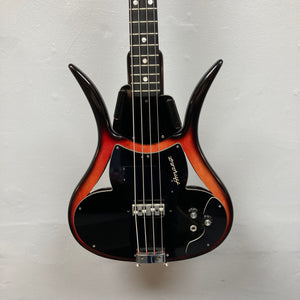 The 1966 Ampeg ASB-1 Devil Bass (Serial #531) is a vintage electric bass guitar featuring a striking sunburst finish and unique horned body shape inspired by the iconic Ampeg design. This classic model comes equipped with three control knobs, a black pickguard, and a bridge-mounted transducer pickup for enhanced tonal versatility. Includes case.