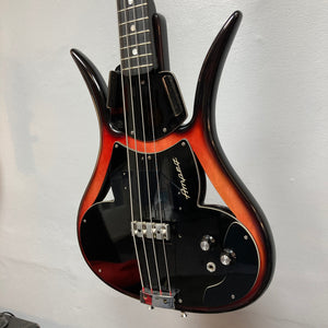 An Ampeg 1966 ASB-1 Devil Bass (Serial #531) with a sunburst finish, black pickguard, two control knobs, and a distinctive body shape hangs on the wall, evoking the classic vintage style of this rare model.