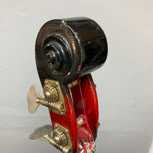 Close-up of the scroll and tuning pegs on an Ampeg 1966 ASB-1 Devil Bass (Serial #531), featuring red varnish and metal hardware reminiscent of a vintage upright, set against a plain gray background.