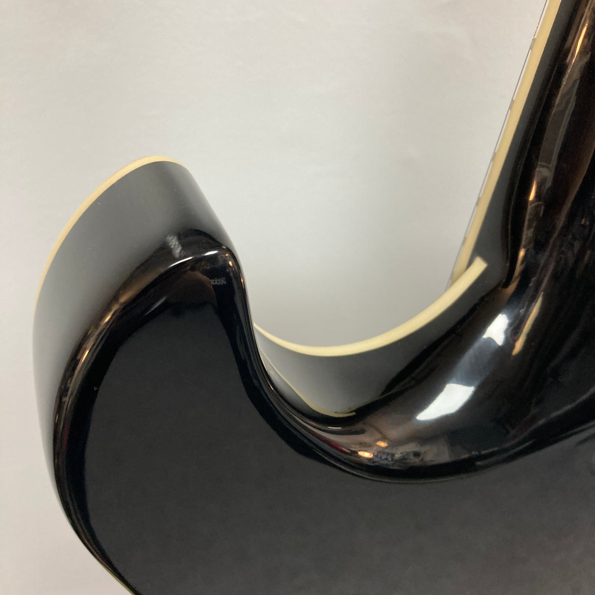 Close-up of a Hagstrom Fantomen Custom Black w/case electric guitar body, featuring its glossy black finish, curved cutaway edge, and cream binding against a plain background.