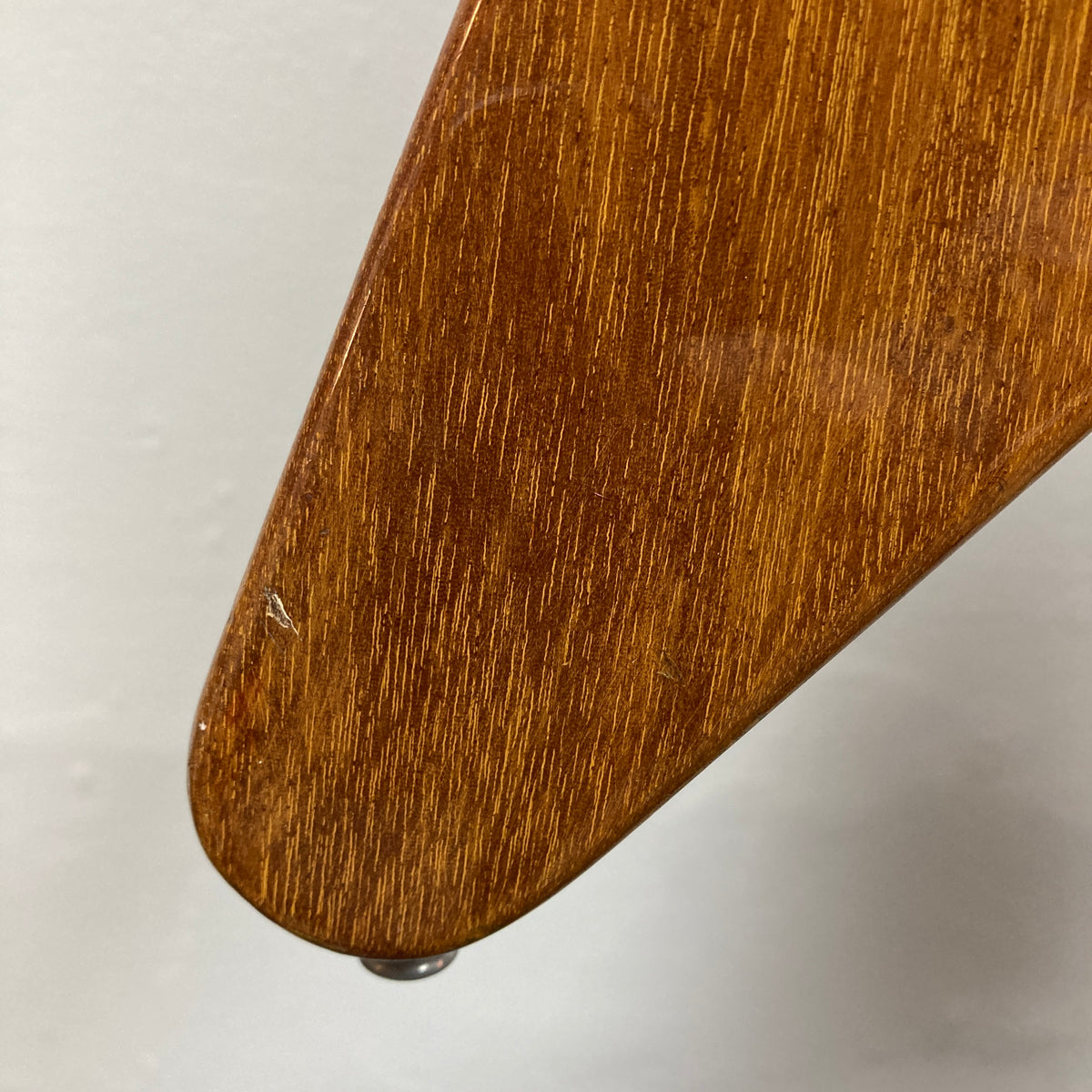 Close-up of a wooden furniture leg featuring a natural finish and glossy sheen, highlighting minor scratches and detailed wood grain reminiscent of the character found in a vintage 1975 Gibson Flying V w/Case by Gibson, set against a plain background.