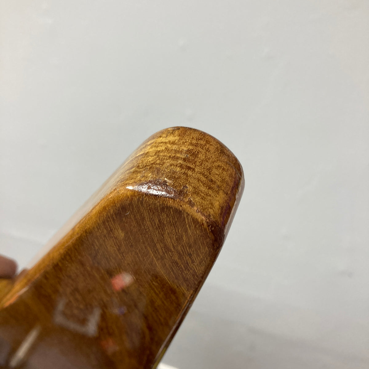 Close-up of the corner of a wooden object with a smooth, polished natural finish and visible wood grain, set against a plain light background—reminiscent of the craftsmanship seen on the 1975 Gibson Flying V w/Case by Gibson.