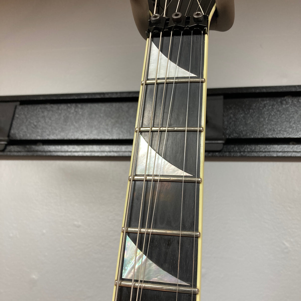 Close-up of the neck of a 1995 Jackson SL1 Soloist Custom Shop Eerie Dess Swirl guitar, highlighting four frets and prominent triangular pearl inlays on a dark fingerboard. Crafted by Jackson in the USA Custom Shop, this high-performance instrument features the striking Eerie Dess Swirl finish for an extra touch of artistry.