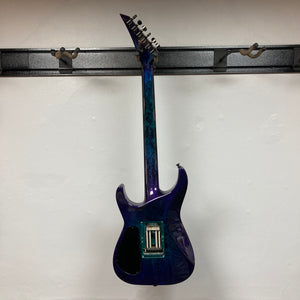 A 1995 Jackson SL1 Soloist Custom Shop electric guitar in Eerie Dess Swirl finish, currently without strings or pickups, is displayed on a black wall mount against a white background, highlighting its premium craftsmanship from Jackson’s USA Custom Shop.