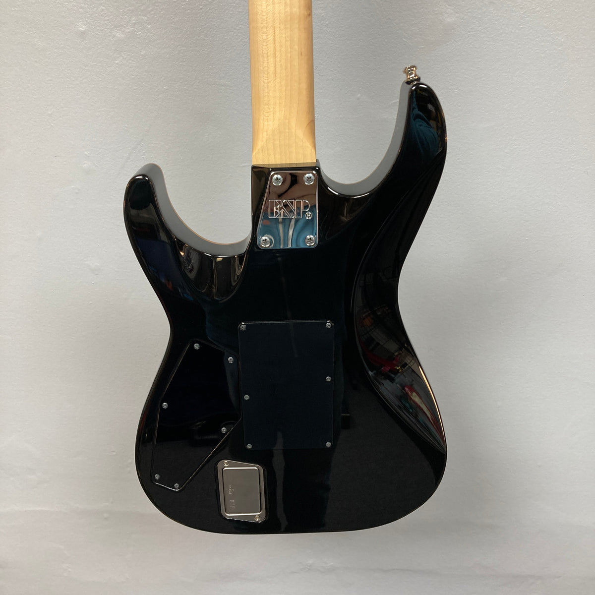 The back of a 2019 ESP USA M-II Purple Haze Burst electric guitar, featuring a natural wood neck and an “ESP” label on the metal neck plate, is displayed against a plain light background. Crafted in the USA by ESP, this guitar highlights superior craftsmanship and striking style.