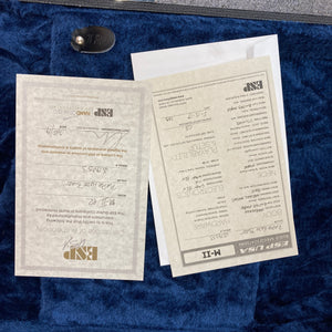 Two ESP specification and warranty cards, one of which features handwritten details, rest atop a blue velvet-lined surface—the perfect accompaniment to your American-made electric guitar, like the striking 2019 ESP USA M-II Purple Haze Burst w/Case from ESP.