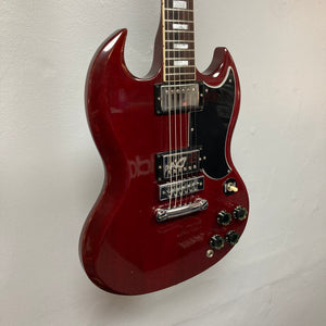 A 1977 Gibson SG Standard Cherry electric guitar by Gibson, featuring a double-cutaway mahogany body, two humbucker pickups, four control knobs, and a black pickguard, displayed against a white wall—a genuine classic from the iconic Kalamazoo era, complete with its original case.
