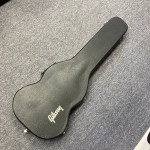 A 1977 Gibson SG Standard Cherry with its original Gibson hard case lies closed on a gray carpeted floor.