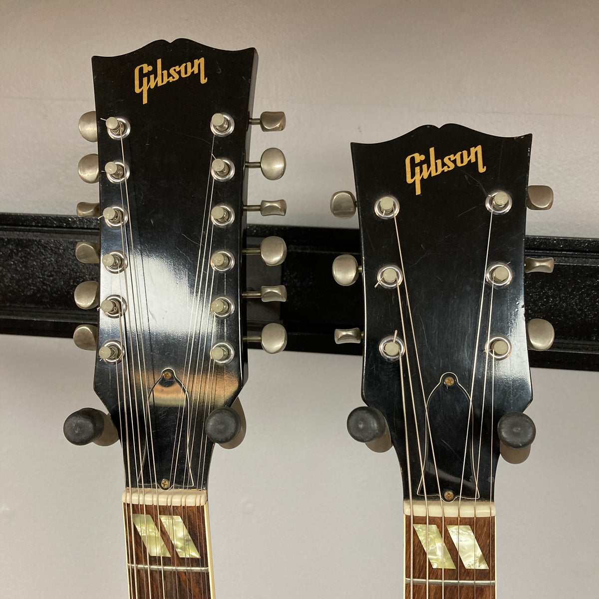 Two Gibson headstocks sit side by side: both from a 1978 Gibson EDS-1275 Double Neck Walnut w/Case. One features twelve tuning pegs for the 12-string neck, while the other has six tuning pegs for the 6-string neck. Both display the iconic gold Gibson logo.