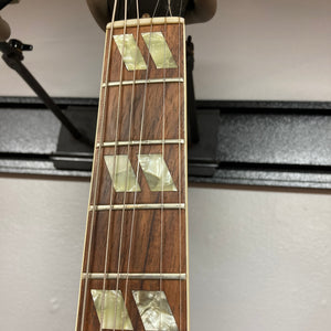 Close-up of a guitar fretboard with mother-of-pearl inlays, displaying metal frets and strings against a white wall background—capturing the distinctive look of the 1978 Gibson EDS-1275 Double Neck Walnut w/Case by Gibson.