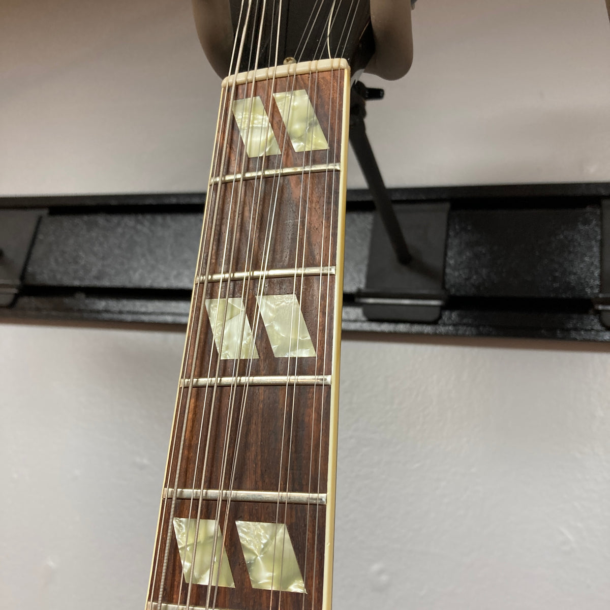 Close-up of the neck of a 1978 Gibson EDS-1275 Double Neck Walnut by Gibson, featuring six strings, a rosewood fretboard, and three pearloid block inlays on the first three frets.