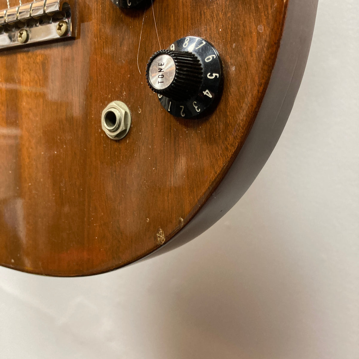 Close-up of the wooden body of a Gibson 1978 EDS-1275 Double Neck Walnut electric guitar, featuring a visible volume knob, input jack, part of the bridge, and a small chip in the finish near the edge.