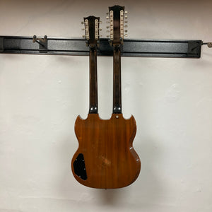 A 1978 Gibson EDS-1275 Double Neck Walnut guitar by Gibson hangs on a wall-mounted rack against a plain white background.