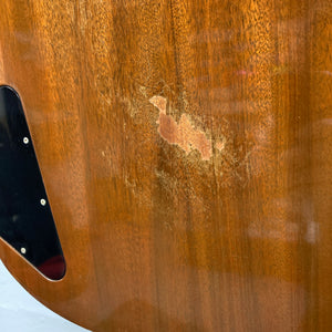 Close-up of the body of a 1978 Gibson EDS-1275 Double Neck Walnut guitar, featuring a worn patch in the finish and exposed wood grain near a black plastic cover.