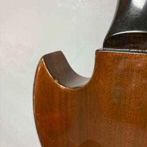 Close-up of a wooden string instrument, its curved edge and part of the neck displayed against a plain light-colored background—a composition reminiscent of classic instruments such as the 1978 Gibson EDS-1275 Double Neck Walnut w/Case by Gibson.