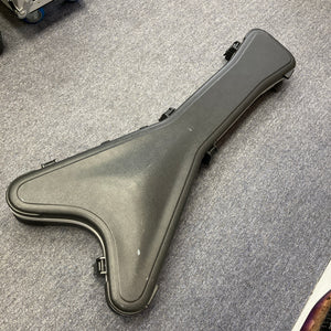 A black, V-shaped Jackson hard guitar case with clasps—designed to fit the signature Phil Demmel Demmelition King V—is shown closed on a gray carpeted floor.