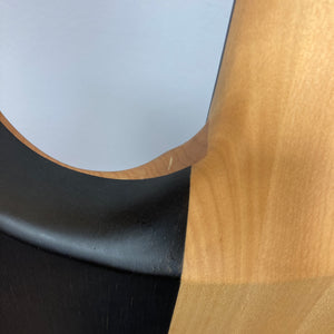 Close-up view of the Chapman ML1 Pro Modern Lunar electric guitar by Chapman, showcasing its elegantly curved body with a smooth gradient transition from natural light wood grain to a sleek black painted section—a hallmark of modern design—featuring dual humbucker pickups.