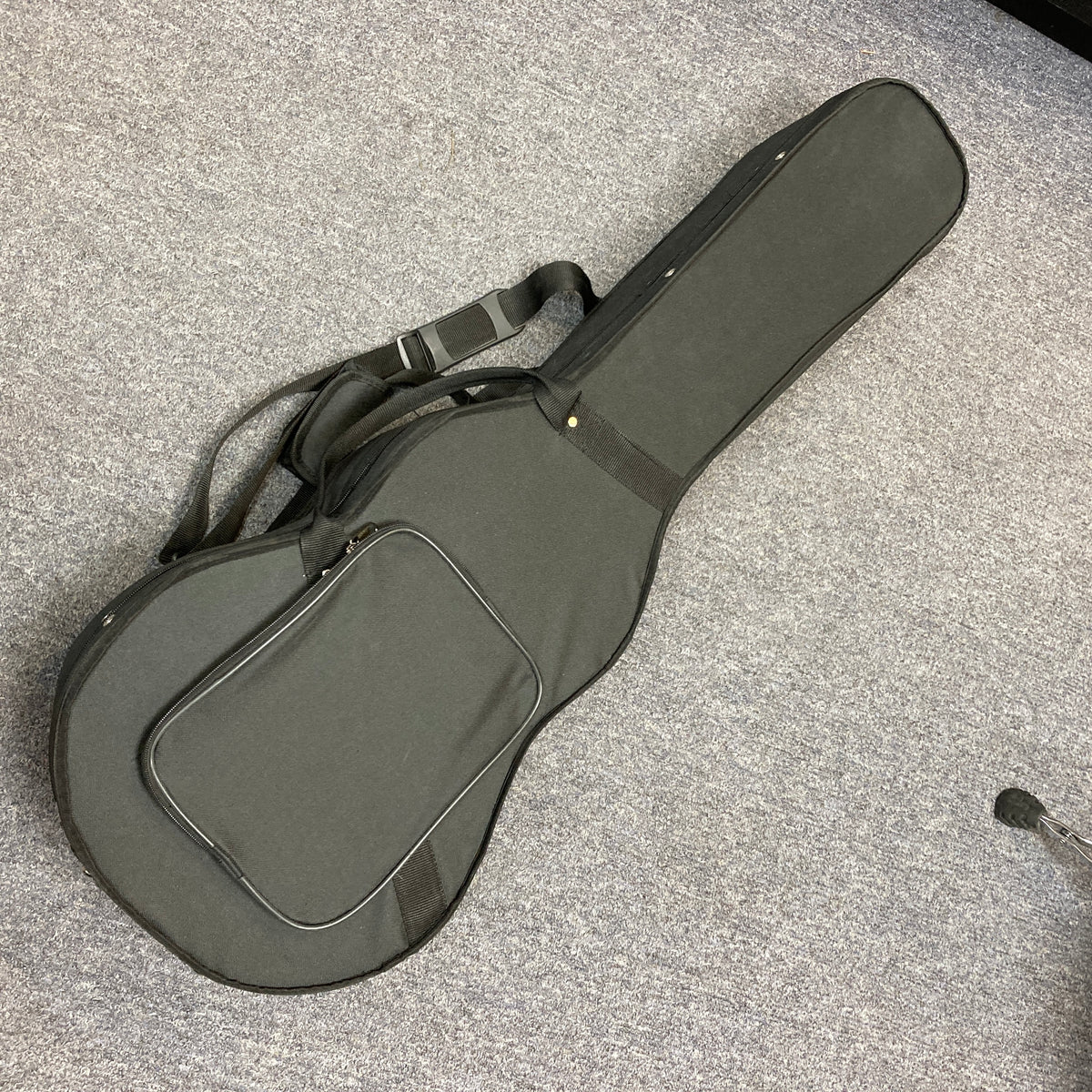 Republic Parlor Resolian Antique Bronze Resonator guitar in its soft black case, featuring a front pocket and shoulder strap, designed to fit this single cone parlor model by Republic, shown lying on a gray carpeted floor.