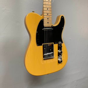 Fender Player Telecaster 75th Anniversary Butterscotch Used electric guitar by Fender, featuring a black pickguard, chrome hardware, and a sleek maple fingerboard, hanging on a light gray wall.