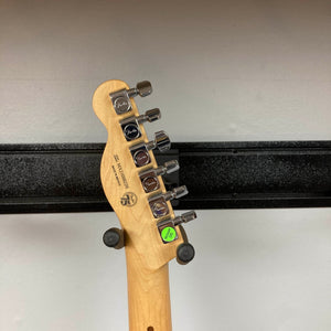 Back of a Fender Player Telecaster 75th Anniversary Butterscotch Used headstock showing six tuning pegs, Fender logos, and a green “2022” sticker. The guitar, finished in classic Butterscotch Blonde with a maple fingerboard, is resting on a wall-mounted hanger.