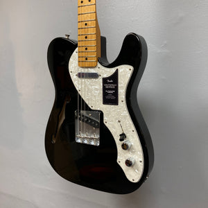 A Fender Vintera II ’60s Telecaster Thinline Black Used electric guitar with a semi-hollow ash body, white pearloid pickguard, maple neck, and vintage-style Tele pickups by Fender hangs on a light gray wall.