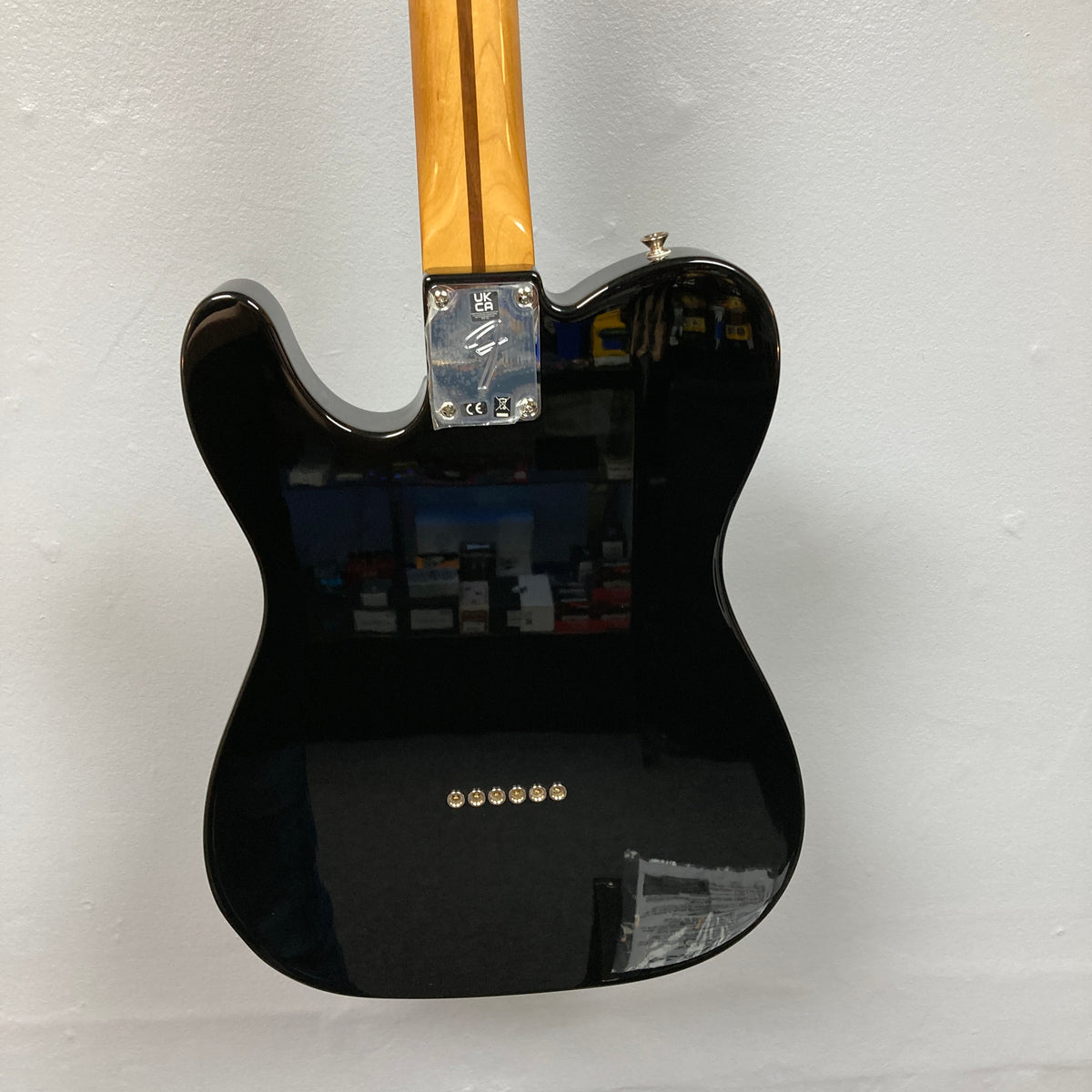 A Fender Vintera II ’60s Telecaster Thinline Black Used electric guitar by Fender is hanging on a white wall with its back facing the camera. Featuring a semi-hollow ash body and vintage-style Tele pickups, this classic guitar showcases both timeless design and rich tone.