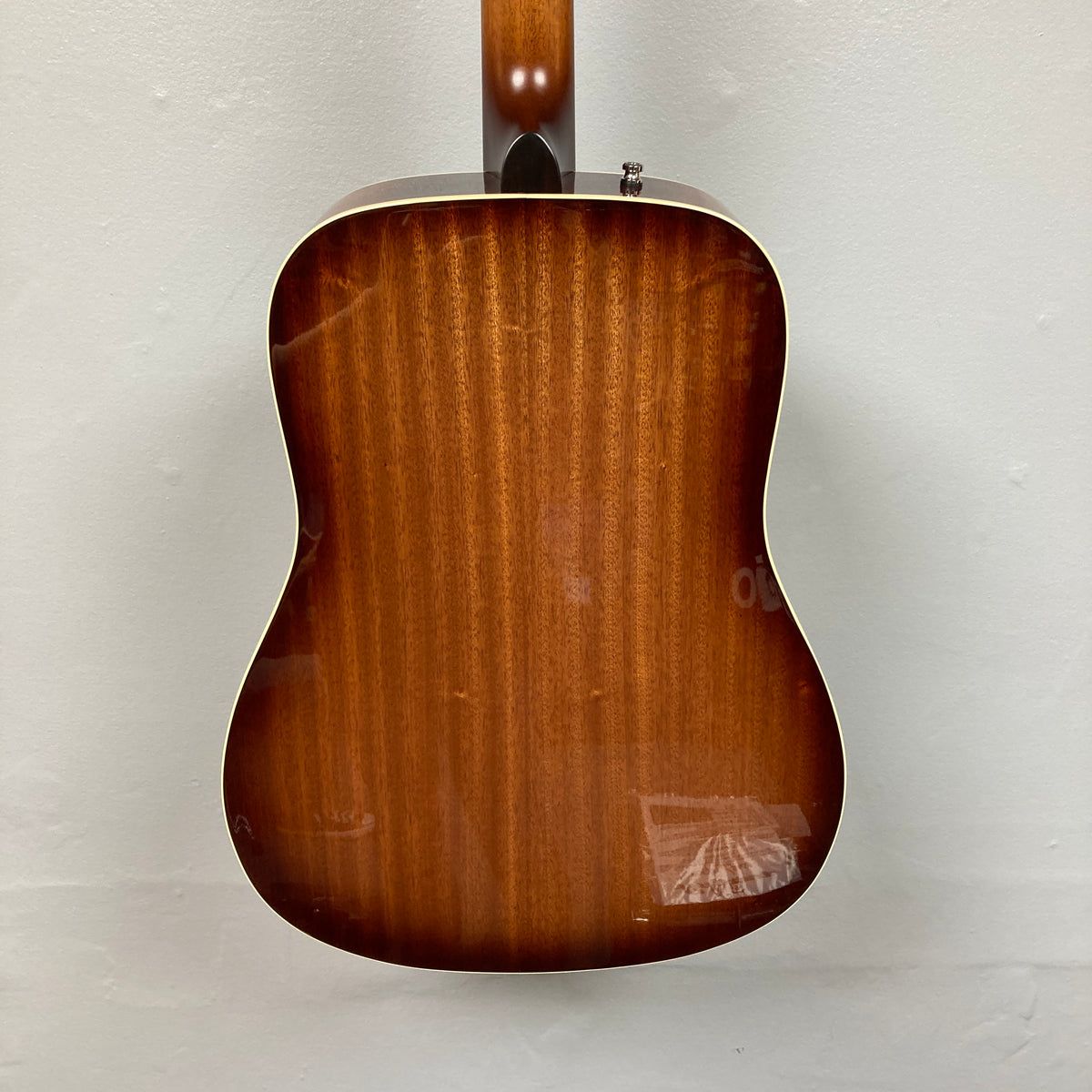 Back view of the Godin Century Maho Rustic Burst EQ SF dreadnought acoustic electric guitar by Godin, featuring a glossy brown wood finish, set against a plain light-colored wall.