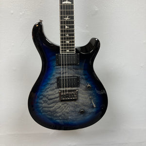 PRS SE Mark Holcomb - Holcomb Blue Burst w/Gigbag Used Consign by PRS, featuring a quilted maple top, Seymour Duncan humbuckers, and bird inlays, shown against a plain light wall.