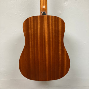 Back view of the Taylor Academy 10e Acoustic-Electric Guitar w/GigBag, natural finish with vertical wood grain patterns against a plain white wall.