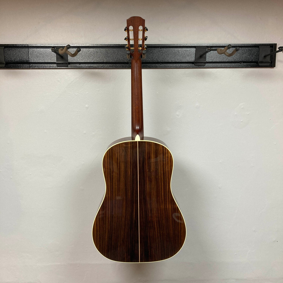 Back view of an Alvarez DYMR70SB Yairi Masterworks Acoustic Guitar Sunburst w/Case Used slope-shoulder dreadnought hanging by its headstock on a wall-mounted hook.