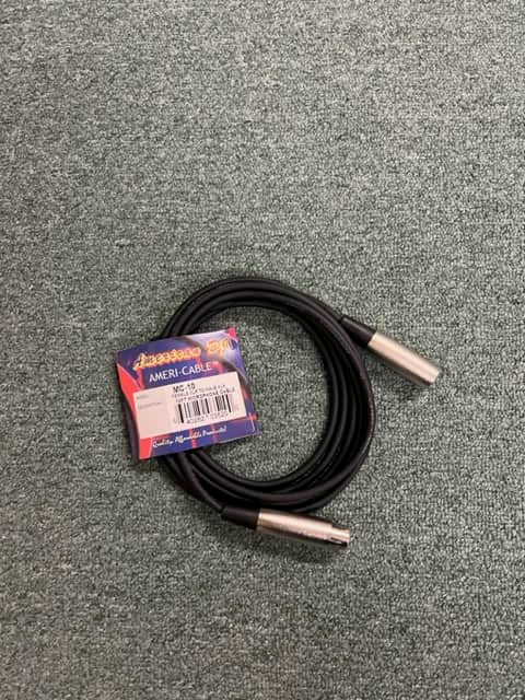 A coiled American DJ MC-10 10ft XLR microphone cable with silver connectors and its label attached lies on a gray carpeted surface.