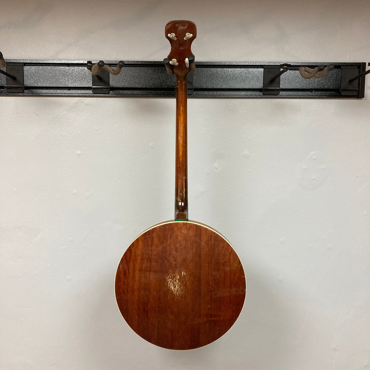 Aria Tenor Banjo 4 String 1970s with case, hanging on a wall, showcasing its high-quality wooden body and resonator, ideal for jazz and Irish music.