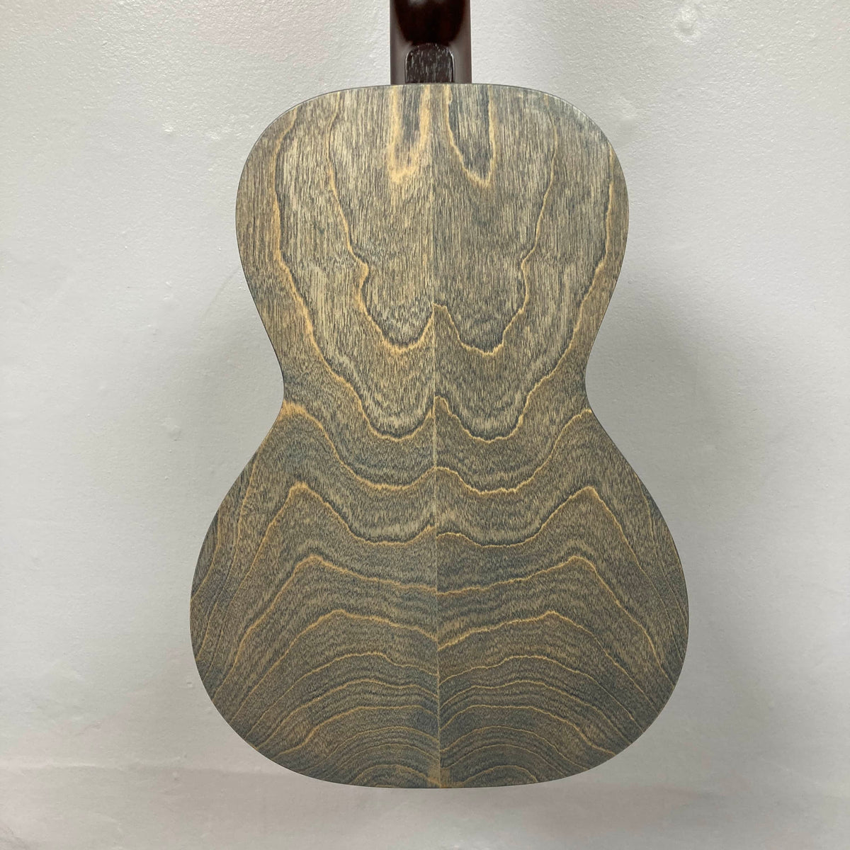 The back of the Art & Lutherie Roadhouse Denim Blue Q-Discrete Parlor Acoustic Guitar displays a wood grain pattern with wavy, symmetrical lines on a light-colored background.