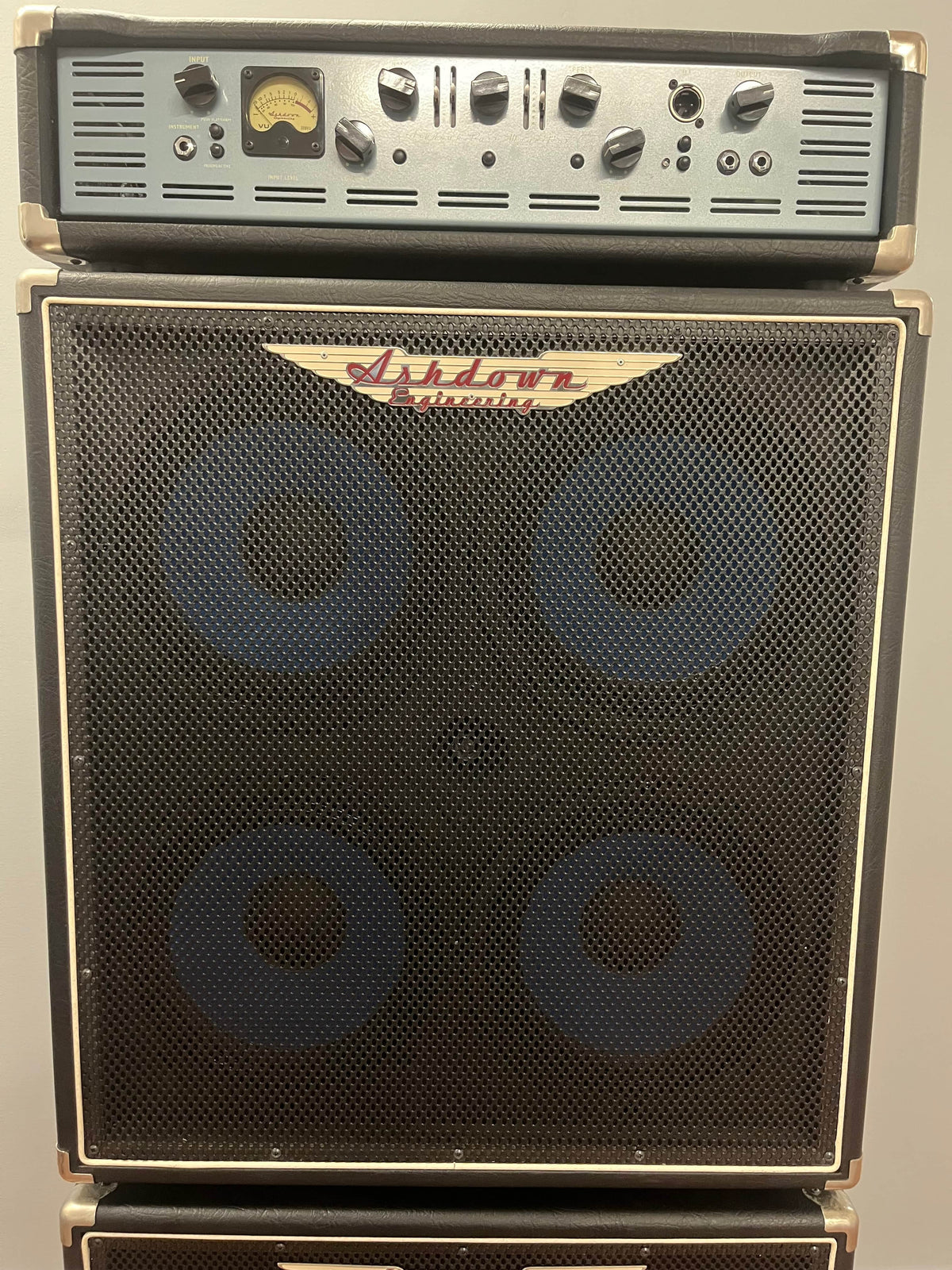 An Ashdown UK Built ABM Bass Rig Full Stack, featuring the EVO II 900 Head with control knobs and meter, sits atop matching 410T and 115-500 cabinets, all by Ashdown.